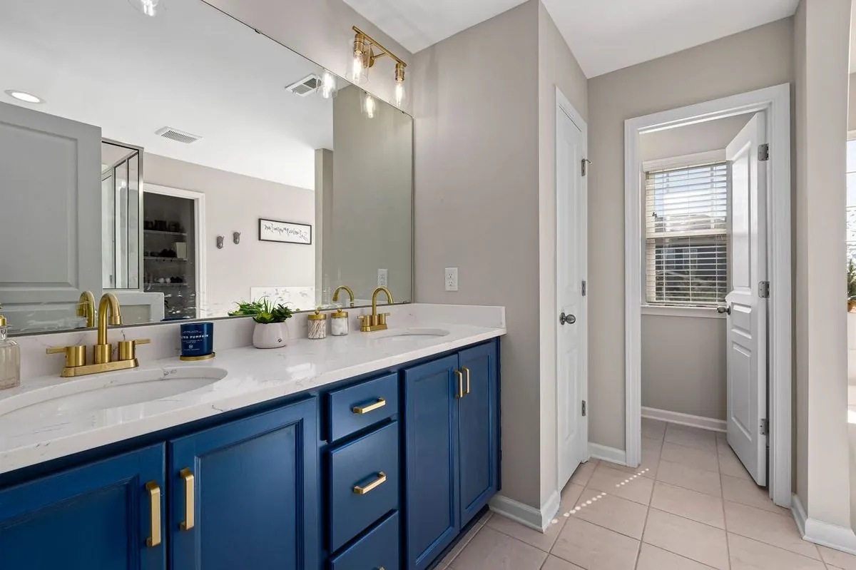 Stylish bathroom featuring a blue vanity, gold fixtures, and decorative accents