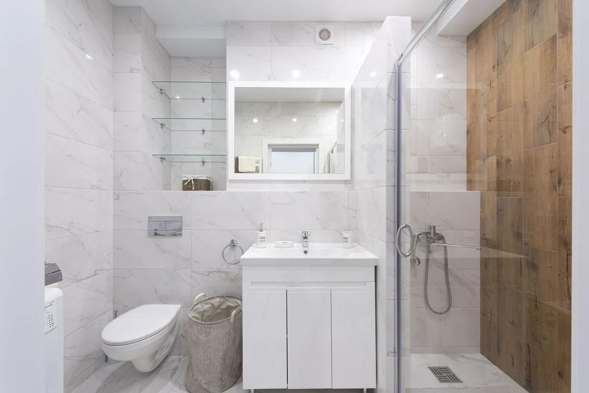 Spacious minimalist bathroom with marble tiles and a glass shower enclosure