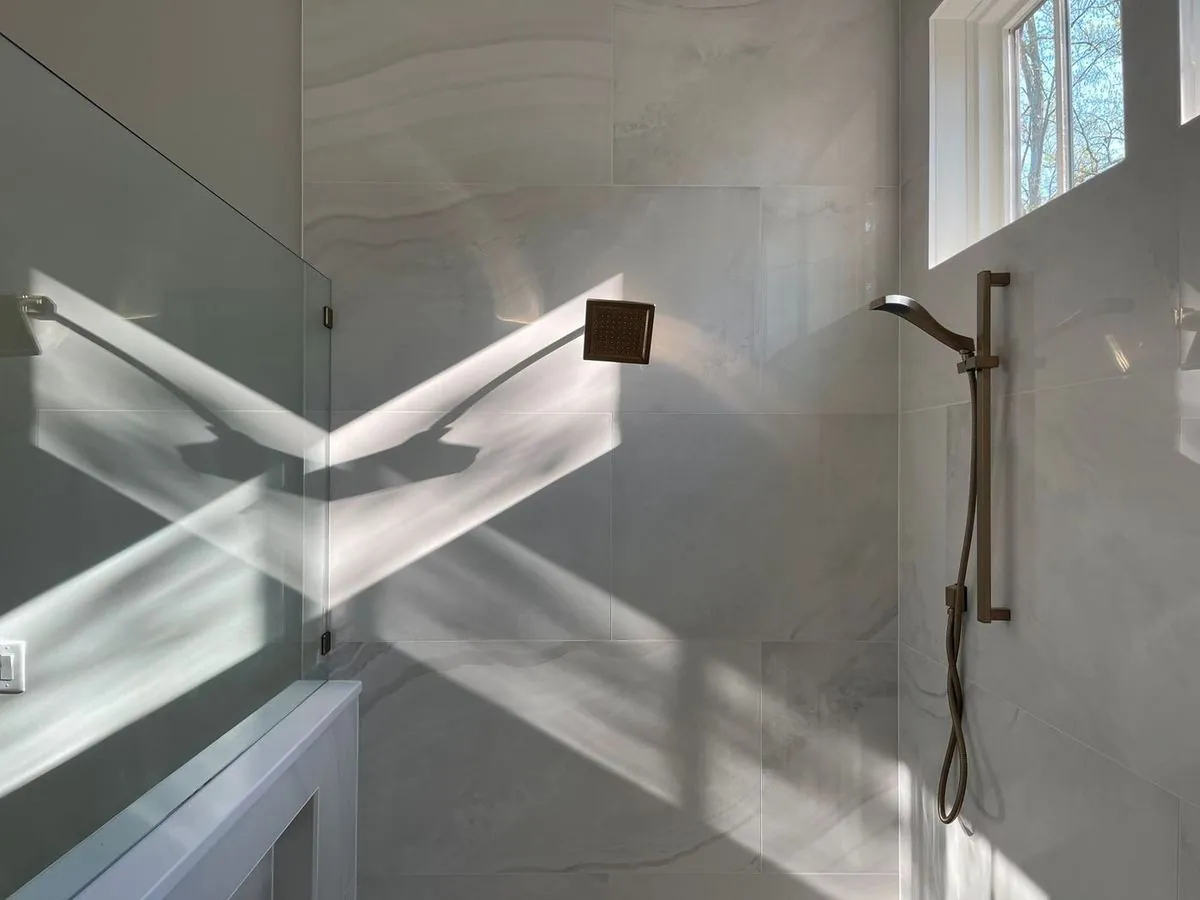 Minimal monochrome bathroom with marble wall, showerhead, and elegant mirror