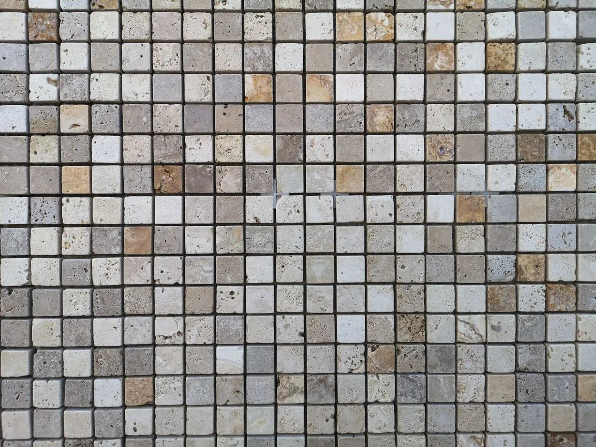 Detailed view of a geometric mosaic tile wall in neutral beige and cream tones