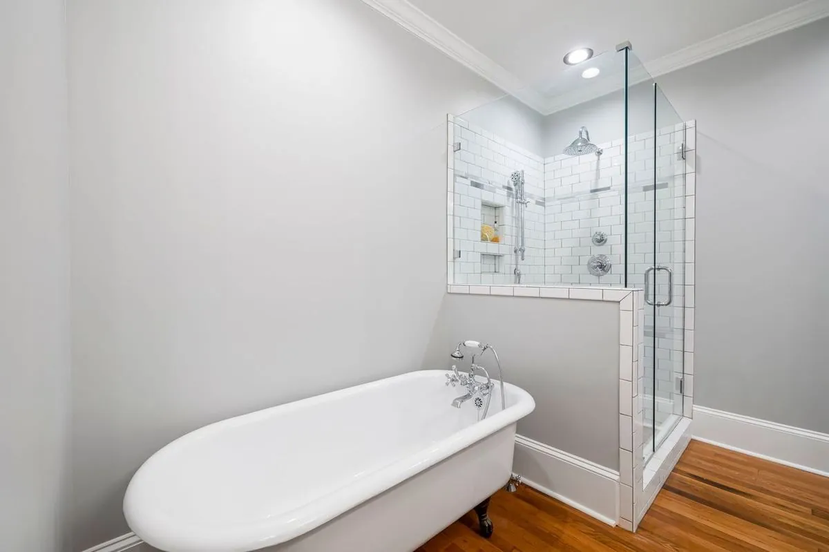 Minimalist bathroom with a clawfoot tub and a glass-enclosed shower.