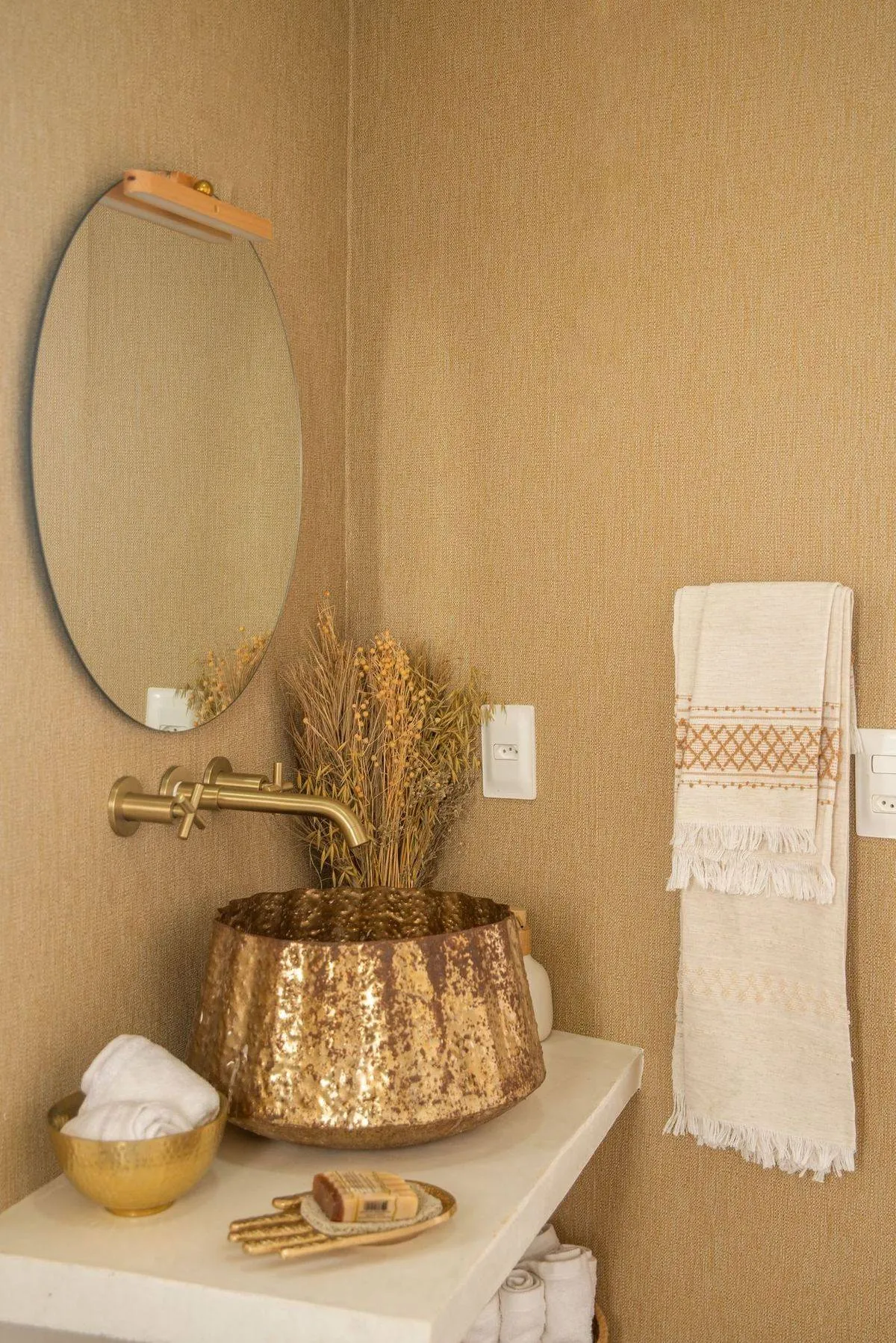 Bathroom with brass fixtures, a round mirror, and modern decor.