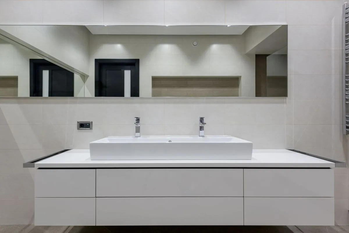 Minimalist bathroom with a large mirror and sleek vanity unit.