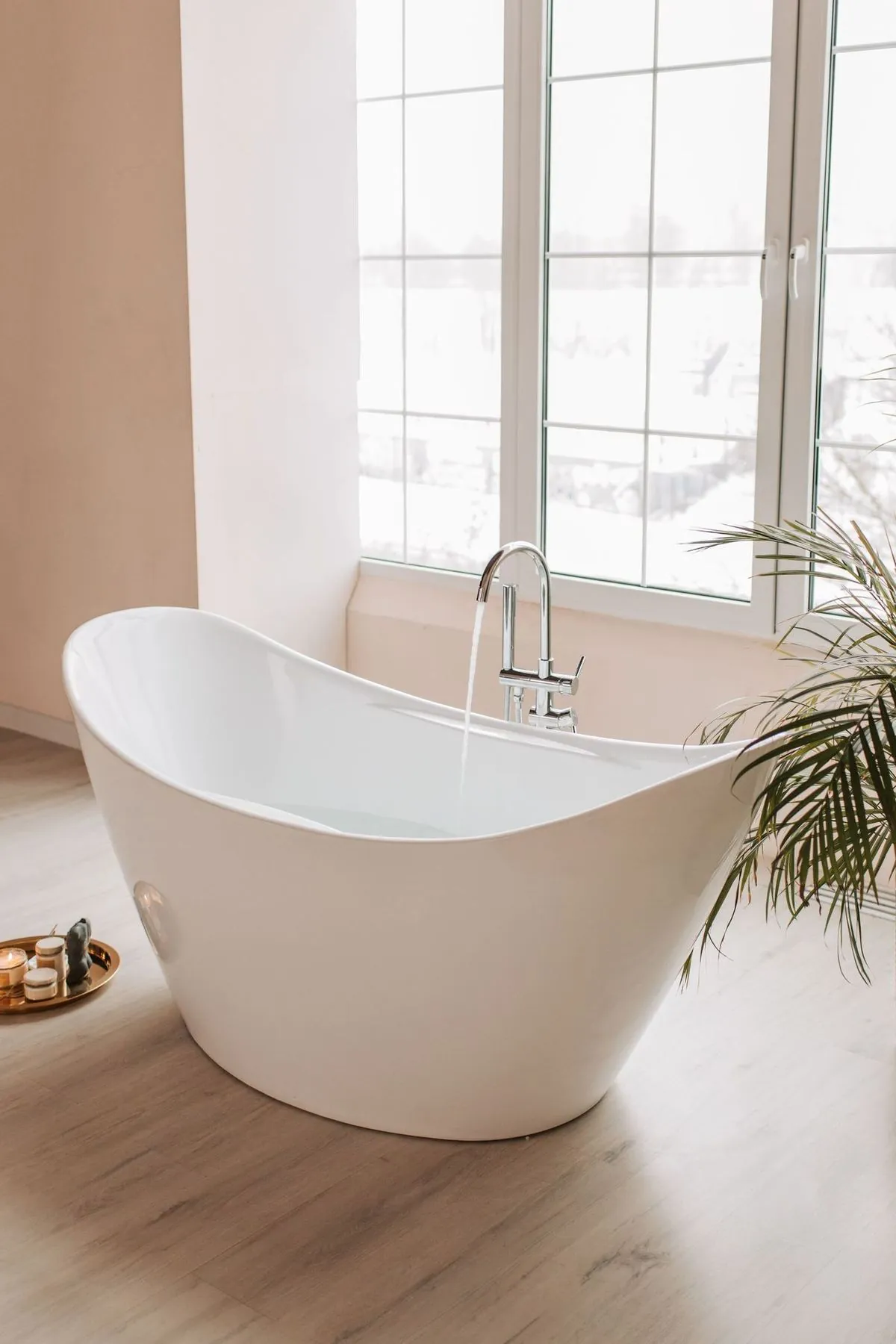 Elegant freestanding bathtub by a large window in a modern bathroom.