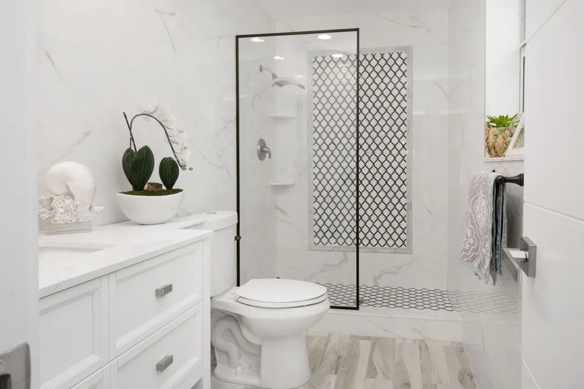Elegant white bathroom with a glass shower and minimalist decor.