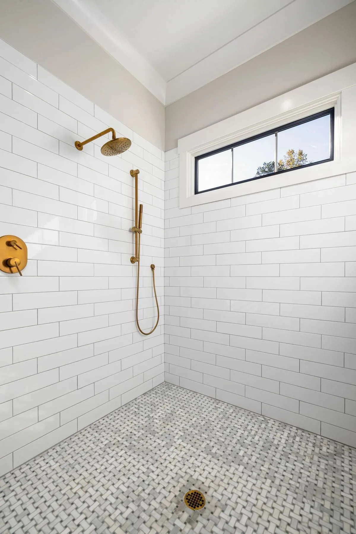 Sleek contemporary bathroom with gold fixtures and white tiles.