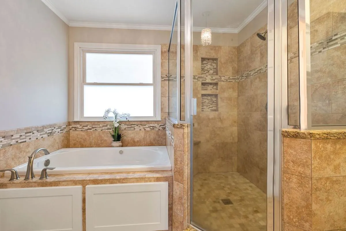 Bathroom with a bathtub and a glass-enclosed shower with elegant tile.