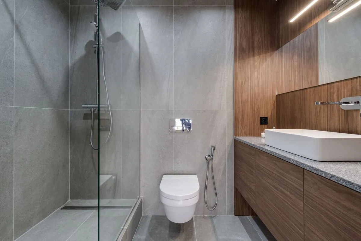 Modern bathroom with a walk-in shower, sink, and wooden finish.