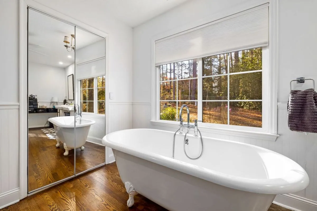 White ceramic bathtub beside tall glass windows in a modern bathroom.