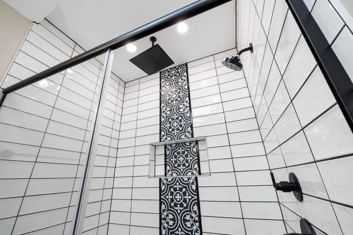Stylish bathroom with a modern shower, patterned tiled wall, and black fixtures.