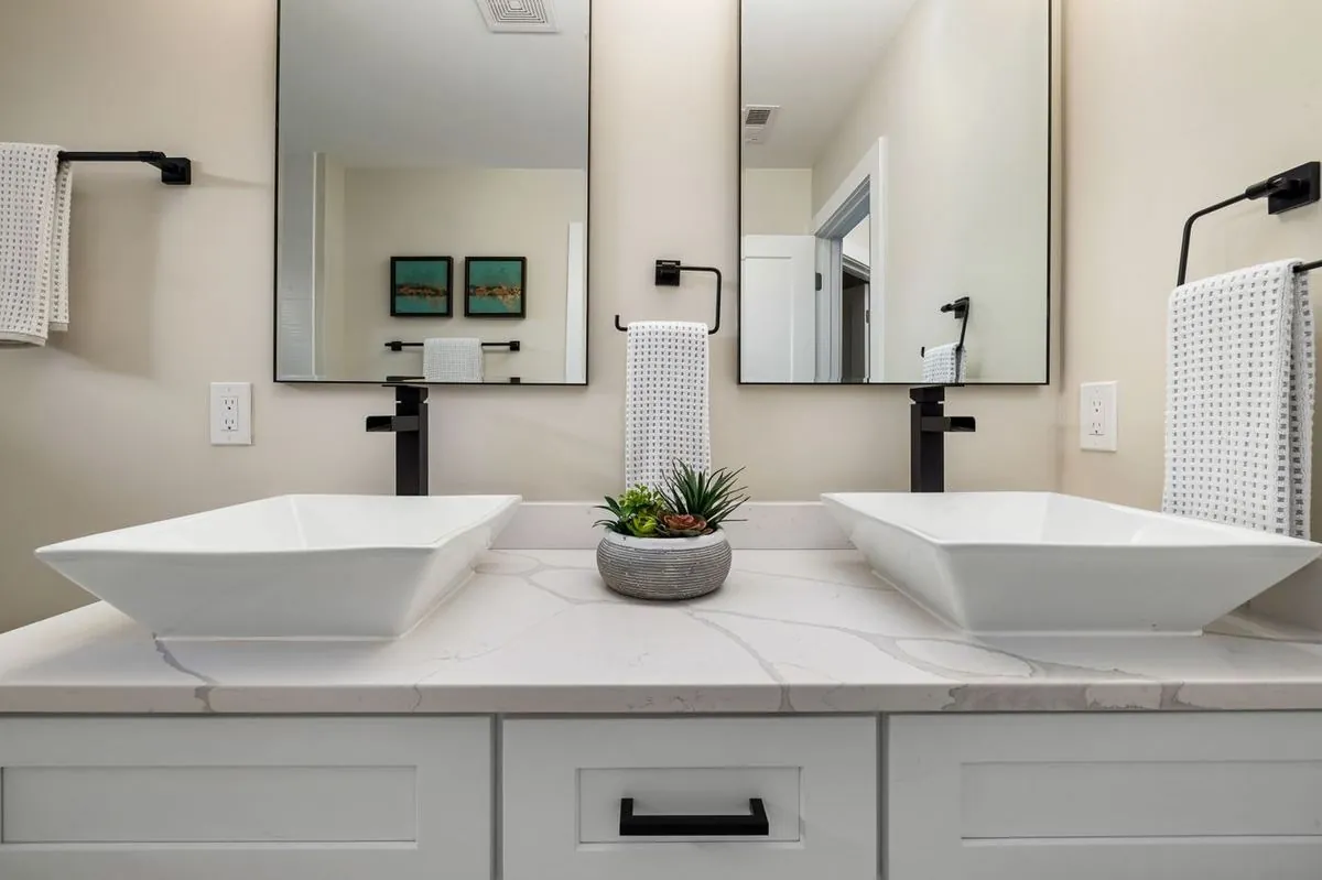 Contemporary bathroom vanity with double vessel sinks, sleek faucets, and large mirrors.