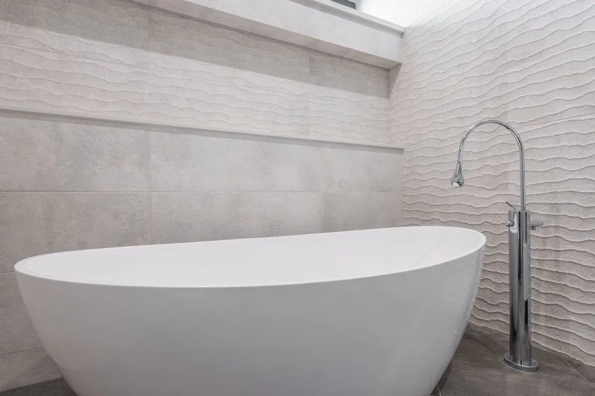 Contemporary bathroom with a sleek white freestanding bathtub and textured walls.