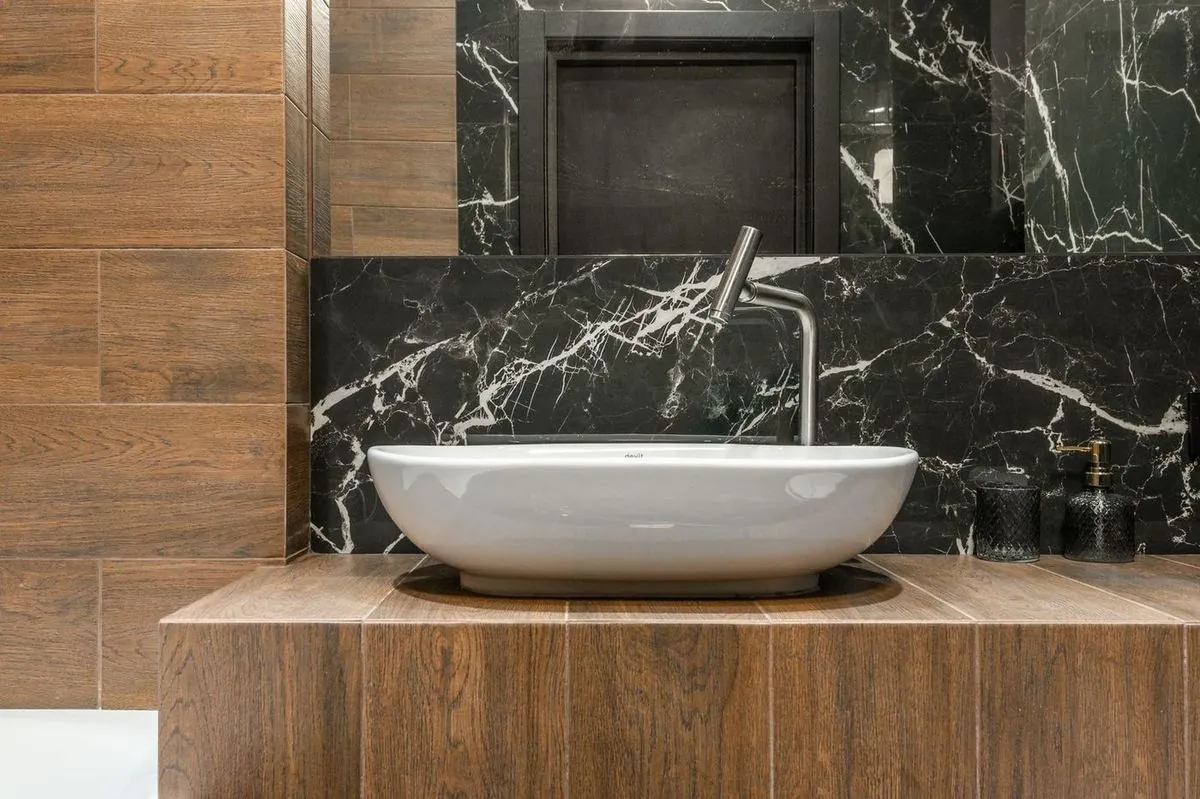 Ceramic washbasin mounted on a wood tile wall.