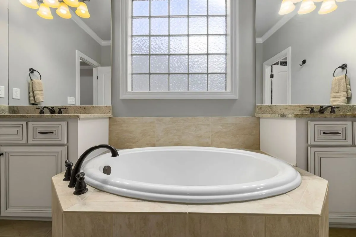 Luxurious bathroom with a marble bathtub, cabinets, and elegant lighting.