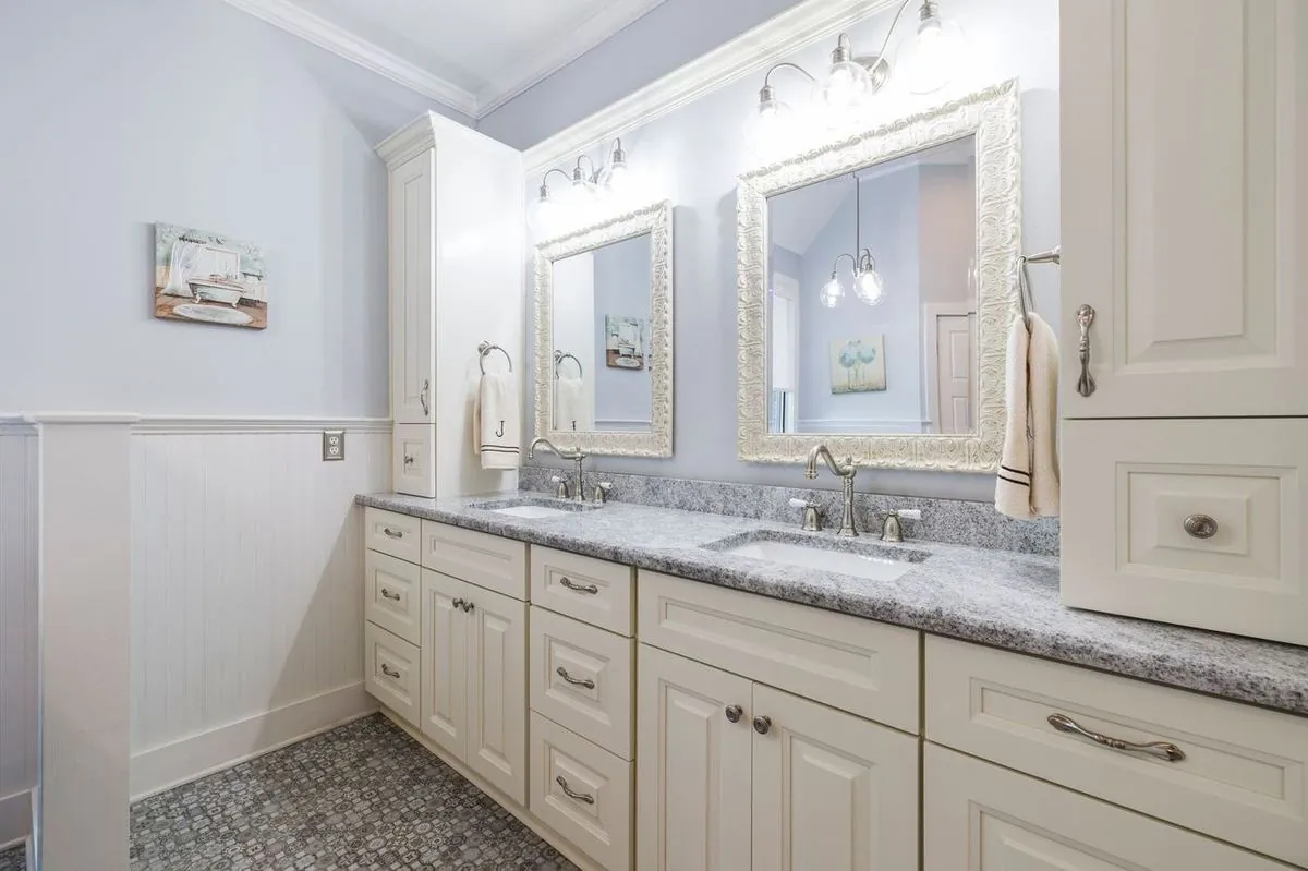 Double-sink vanity with gray granite countertop, white cabinets, and large mirror