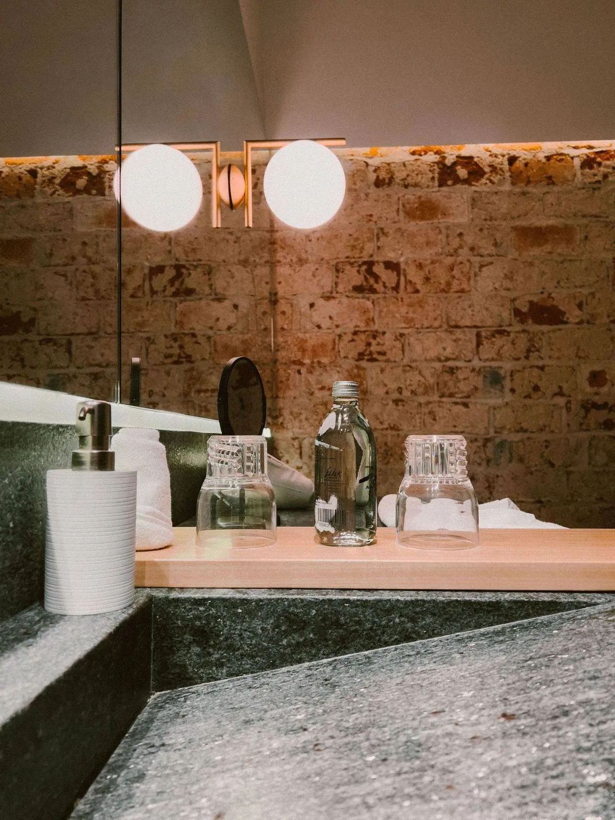 Stylish bathroom vanity with brick wall, mirror, and decor accents