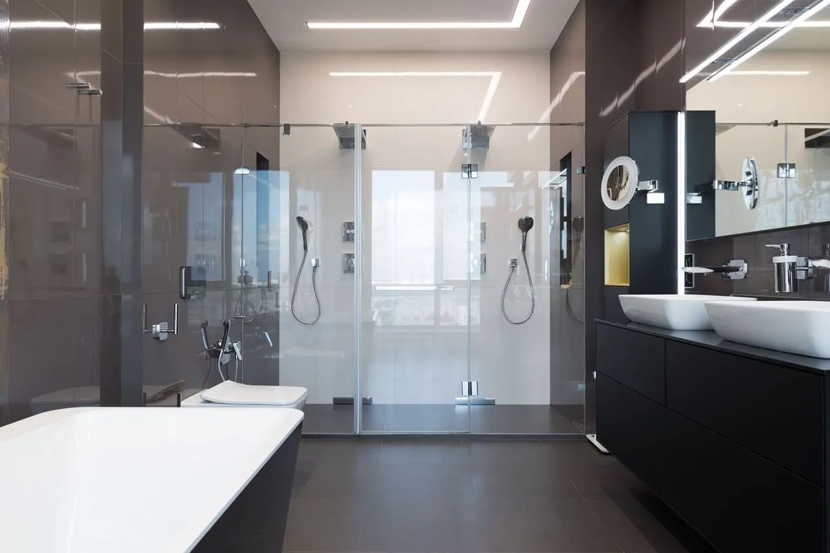 Illuminated modern bathroom with bathtub, glass shower cabin, dual sinks, and chrome fixtures