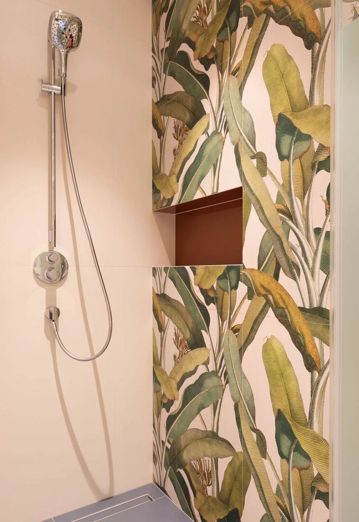 Bathroom interior with shower near a colorful floral accent wall and shelf.