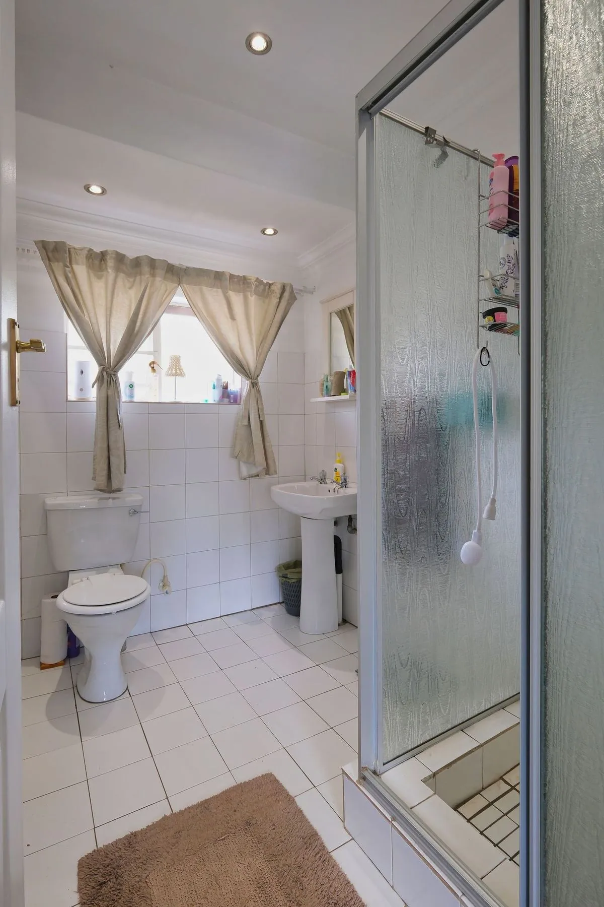 Bright and contemporary bathroom interior showcasing a shower, toilet, and sink.