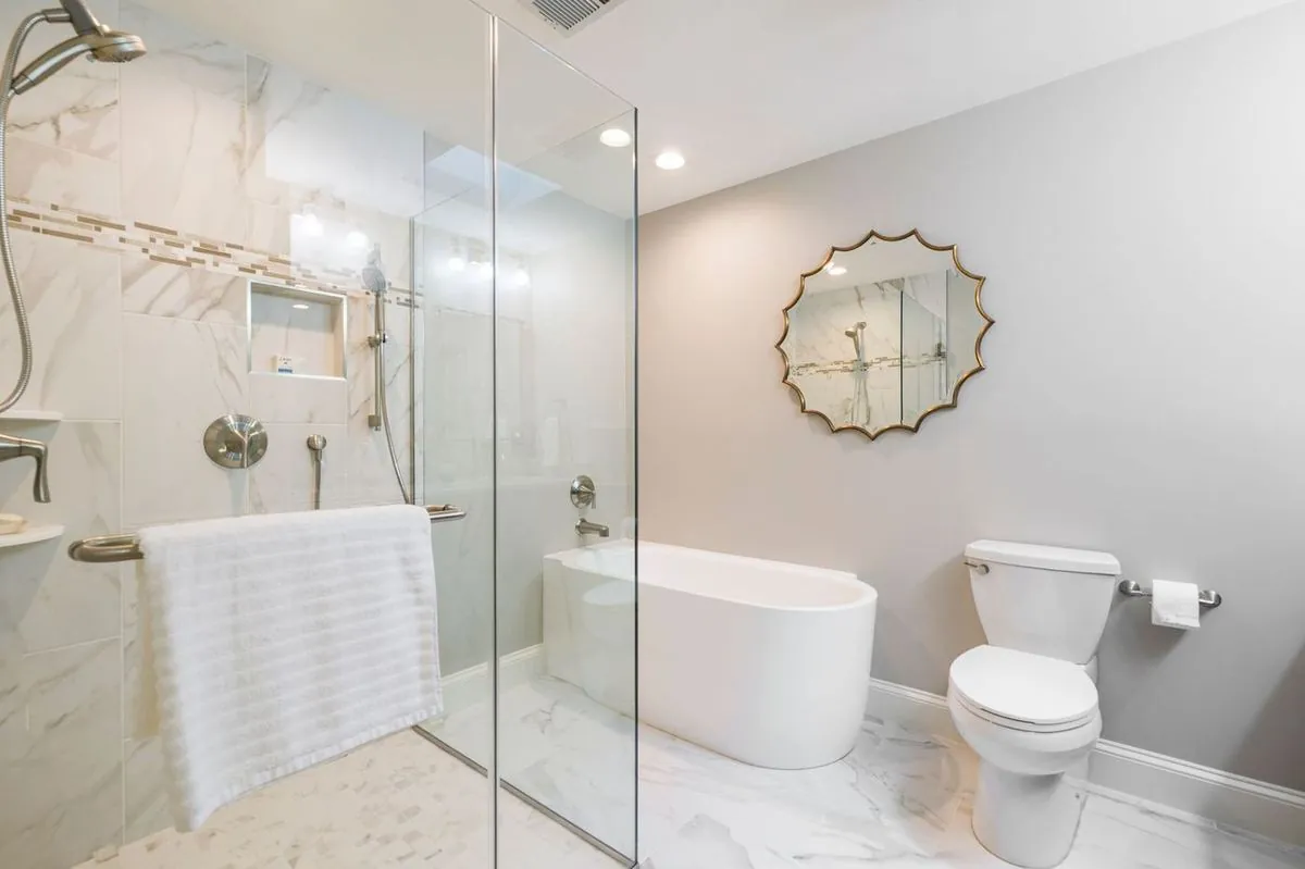Marble walk-in shower with glass enclosure and freestanding tub.