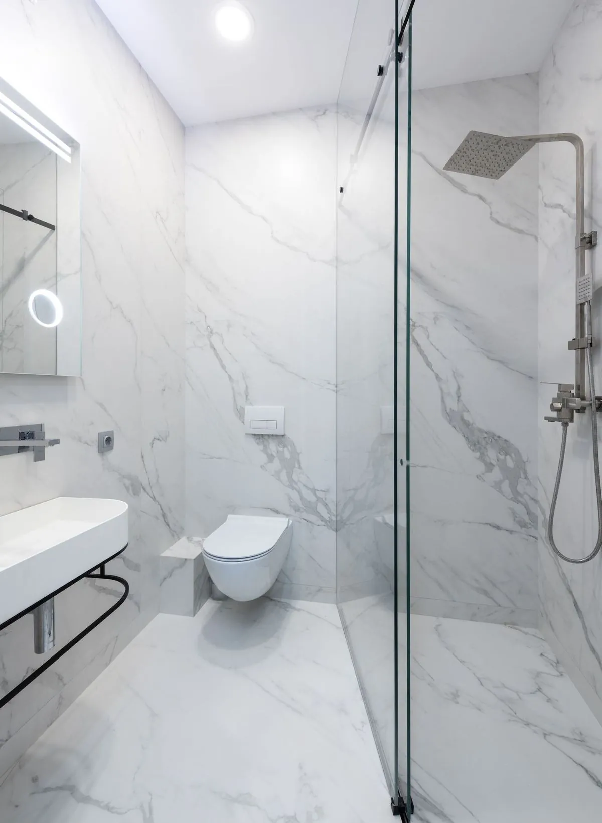 White marble walk-in shower with rain showerhead and glass door.