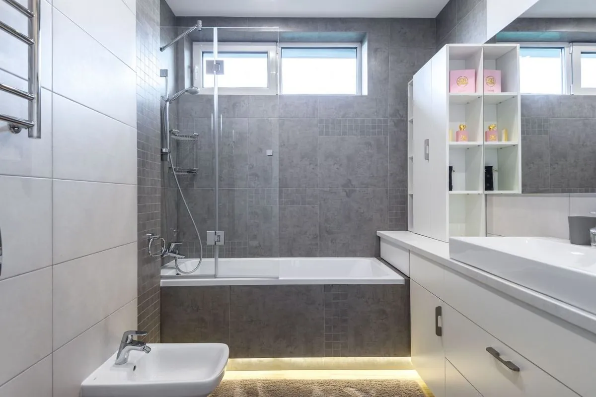 Contemporary bathroom with sleek gray tiles, bathtub, shower, and vanity.