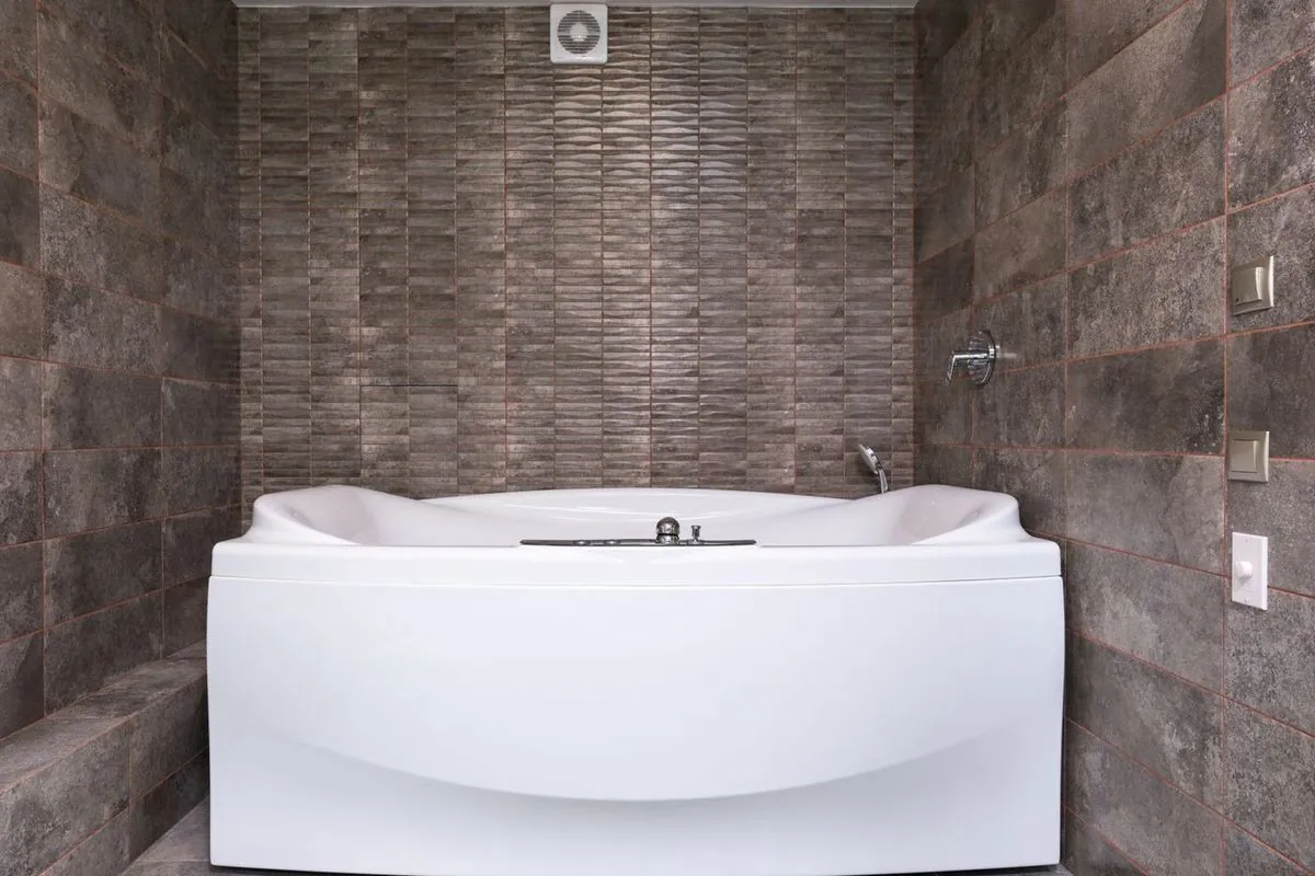 Modern bathtub in a bathroom with tiled walls.