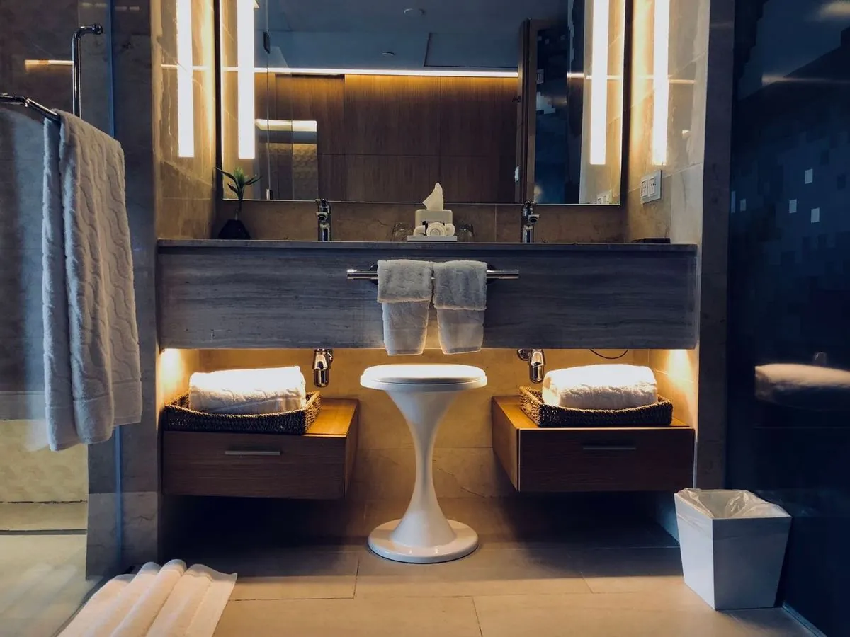 Stylish modern bathroom with illuminated vanity, large mirrors, and warm cozy lighting.