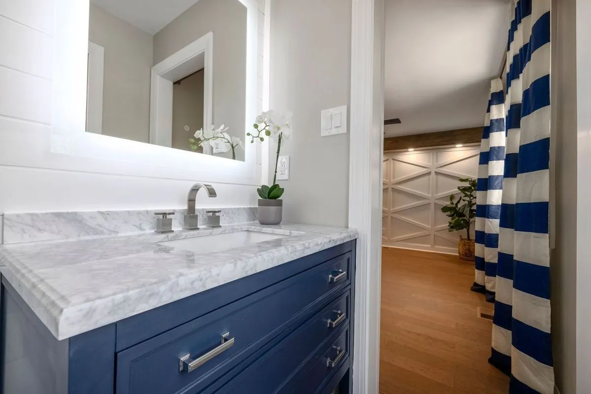Elegant bathroom interior with marble vanity, illuminated mirror, and blue accents for a contemporary feel