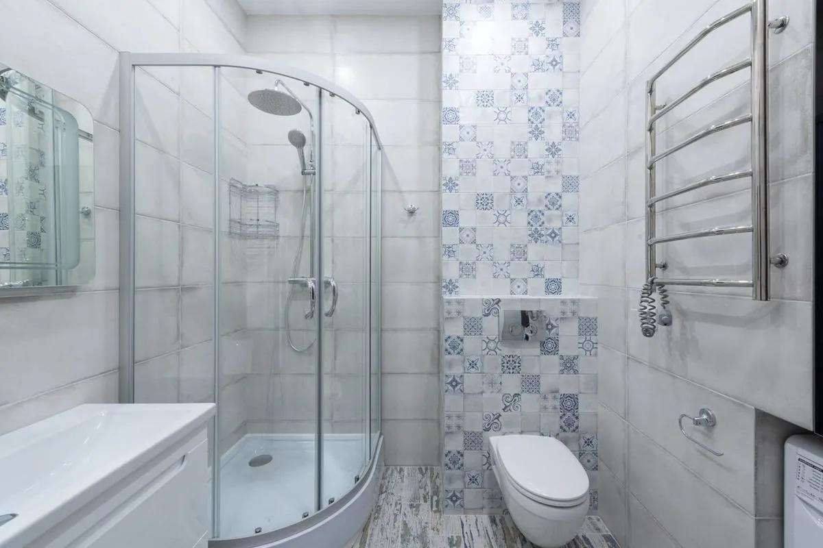 Bright and clean modern bathroom with glass shower and tiled walls.