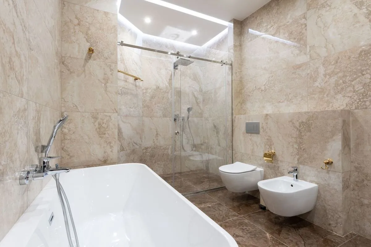 Spacious marble bathroom with a bathtub, glass shower, and modern fixtures.