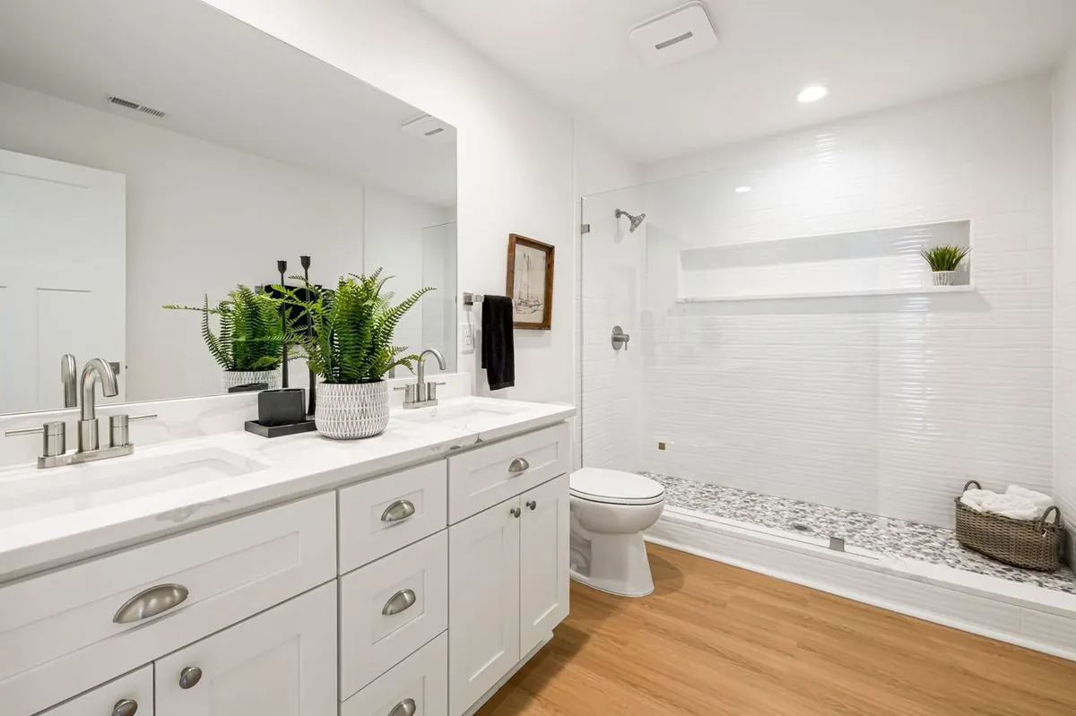 Elegant bathroom with double vanity, glass shower, and indoor plants for a modern touch.