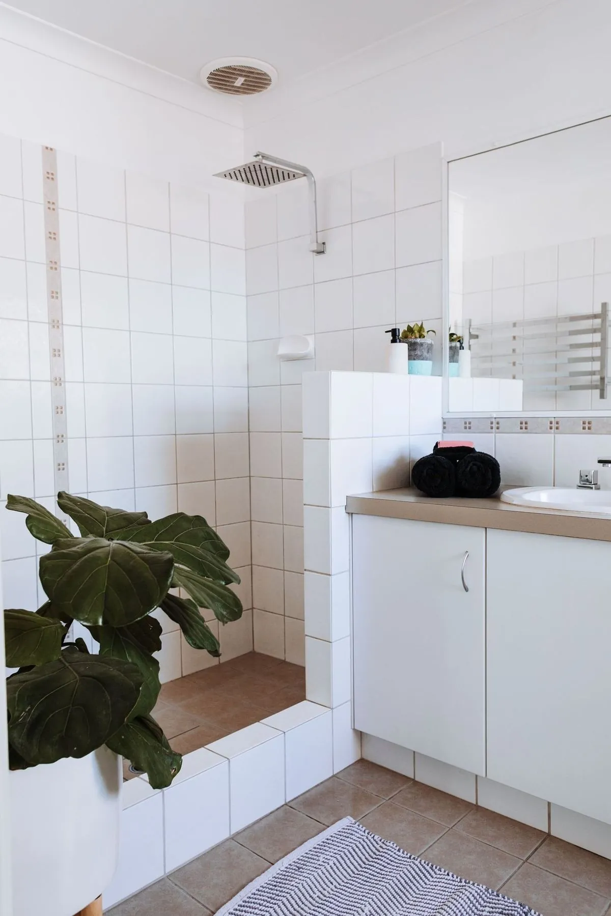 Bright and modern minimalist bathroom with white tiles and green plant