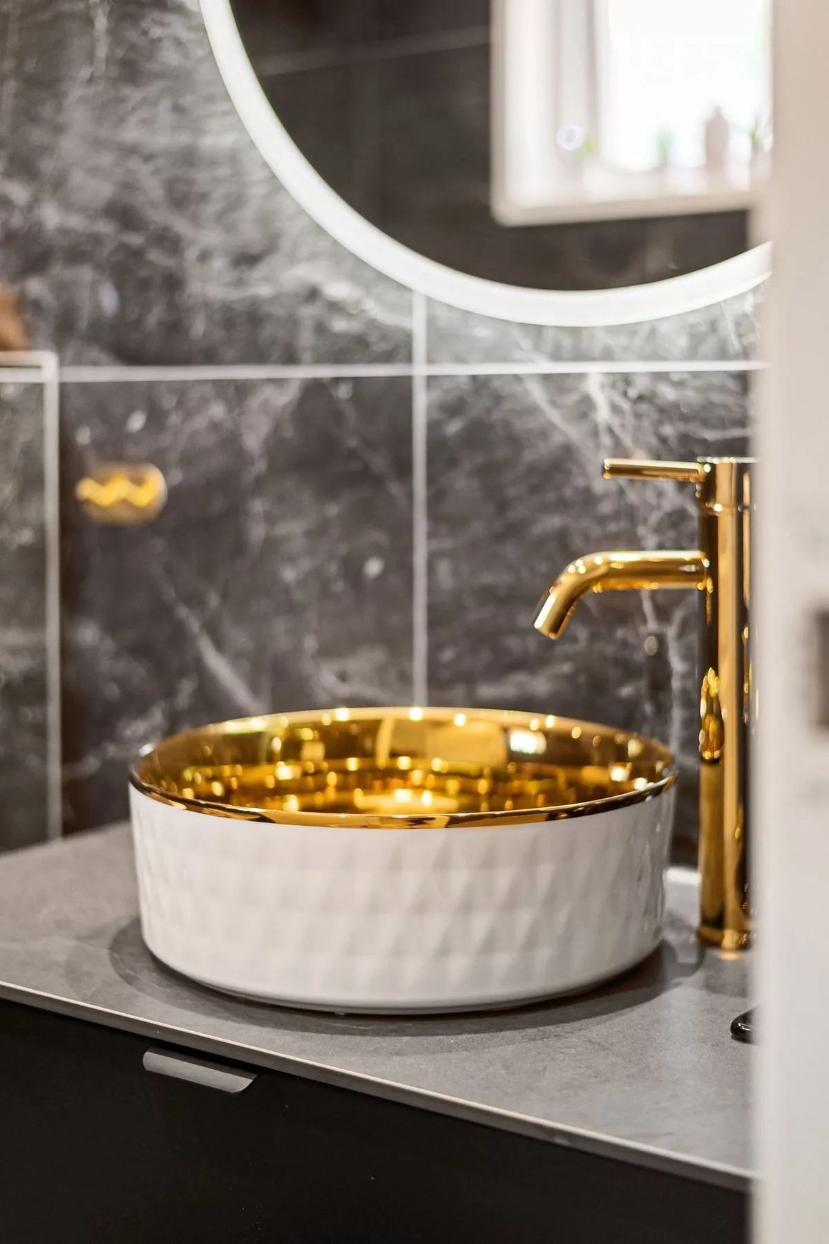 Luxury bathroom sink with a golden faucet and modern fixtures.