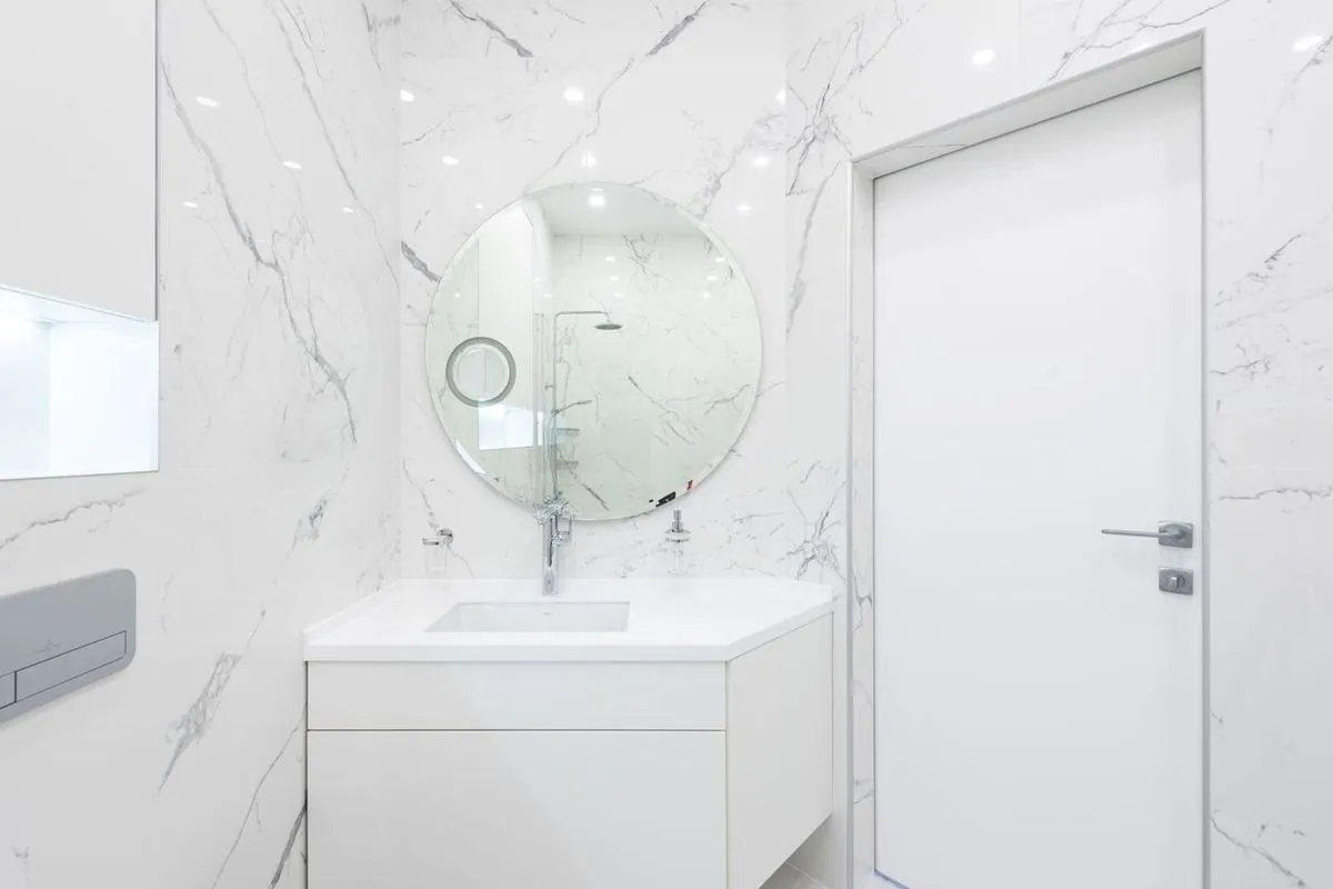 Washroom interior with cabinet, sink, and mirror near the door