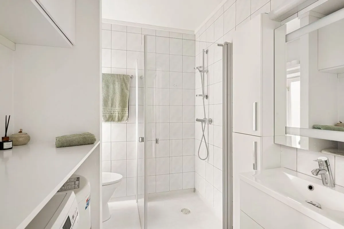 Bright, minimalist white bathroom featuring a sleek design with glass shower and modern fixtures