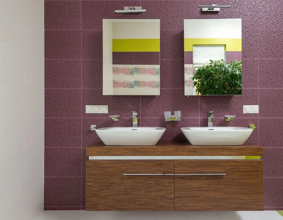 Bathroom with colorful mosaic tile wall, wooden vanity, and dual mirrors