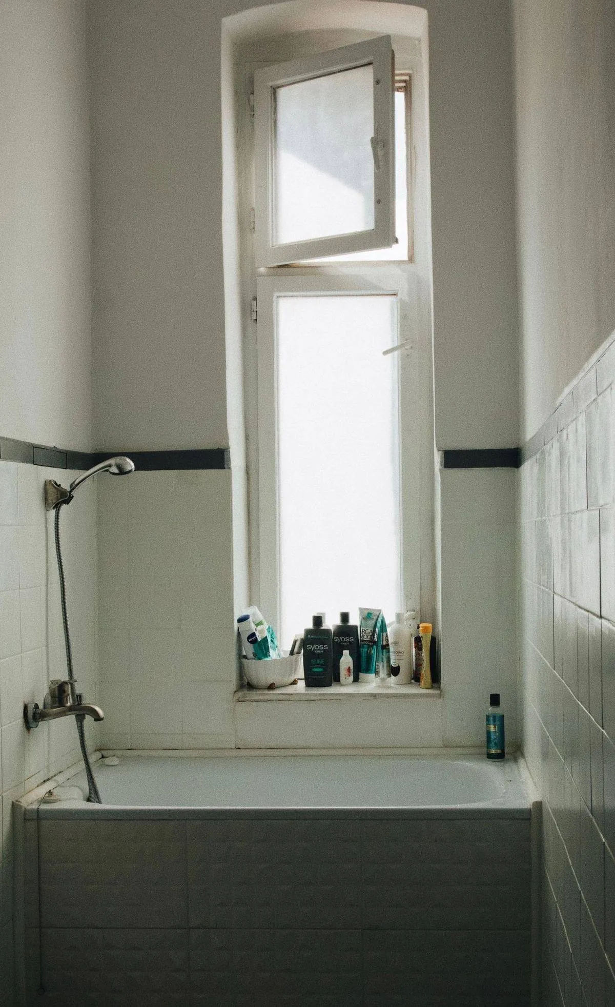Vintage-style bathroom with a tall window above the bathtub