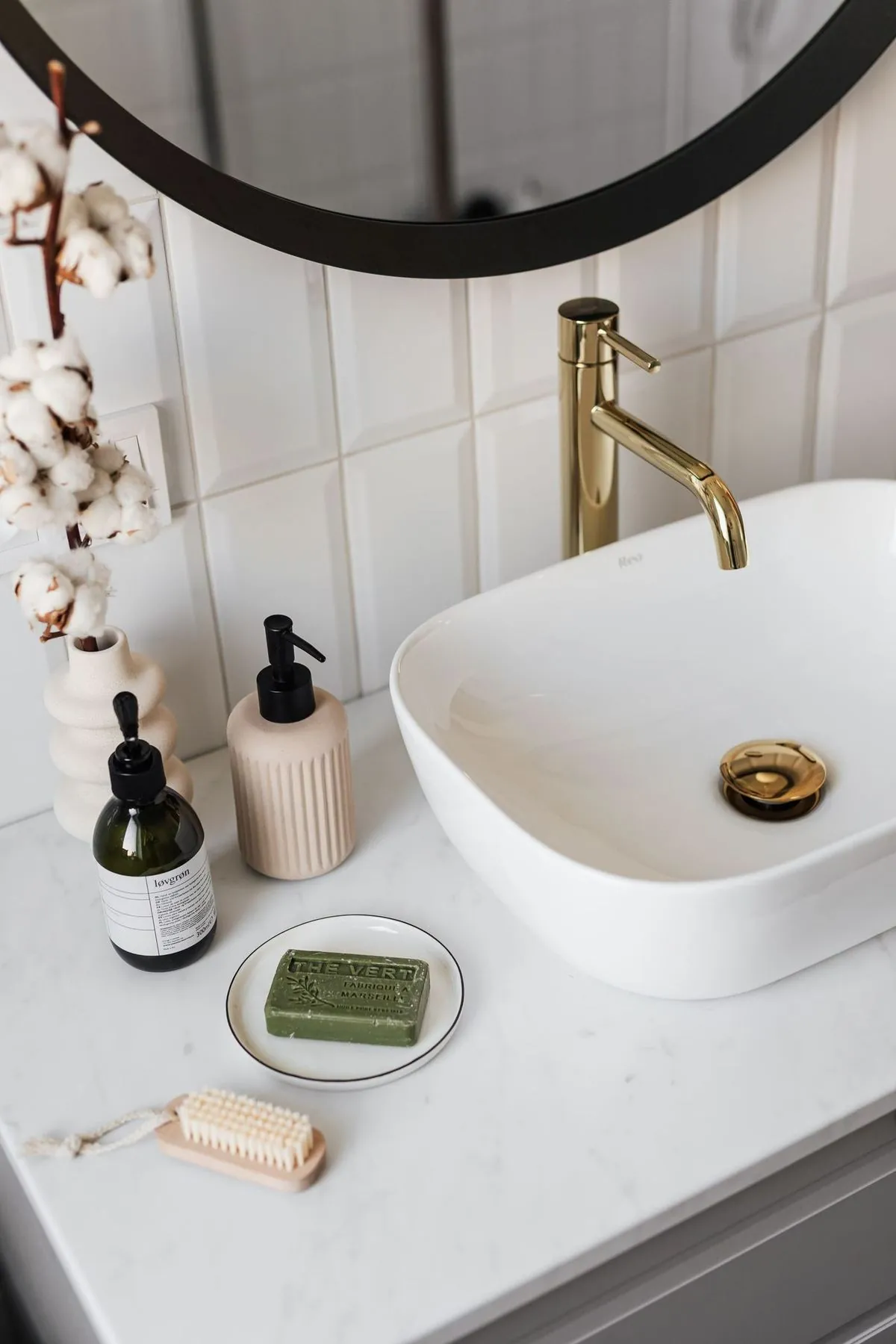 Stylish bathroom vanity featuring a ceramic sink, gold faucet, and spa-like accessories