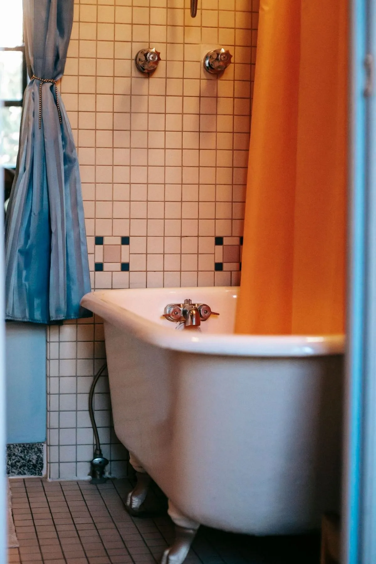 Bathroom interior with orange curtains and tiled floor and walls