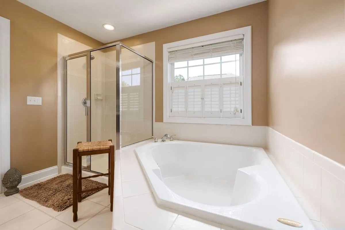 Bright spacious bathroom with large bathtub and glass shower enclosure