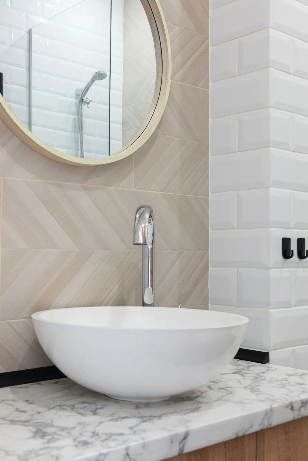 Contemporary bathroom with white vessel sink, round mirror, and marble countertop