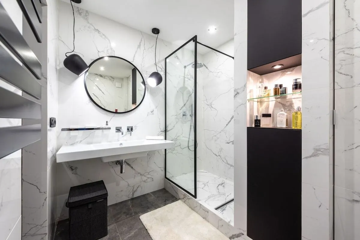 Sleek modern bathroom with marble walls, glass shower, and vanity
