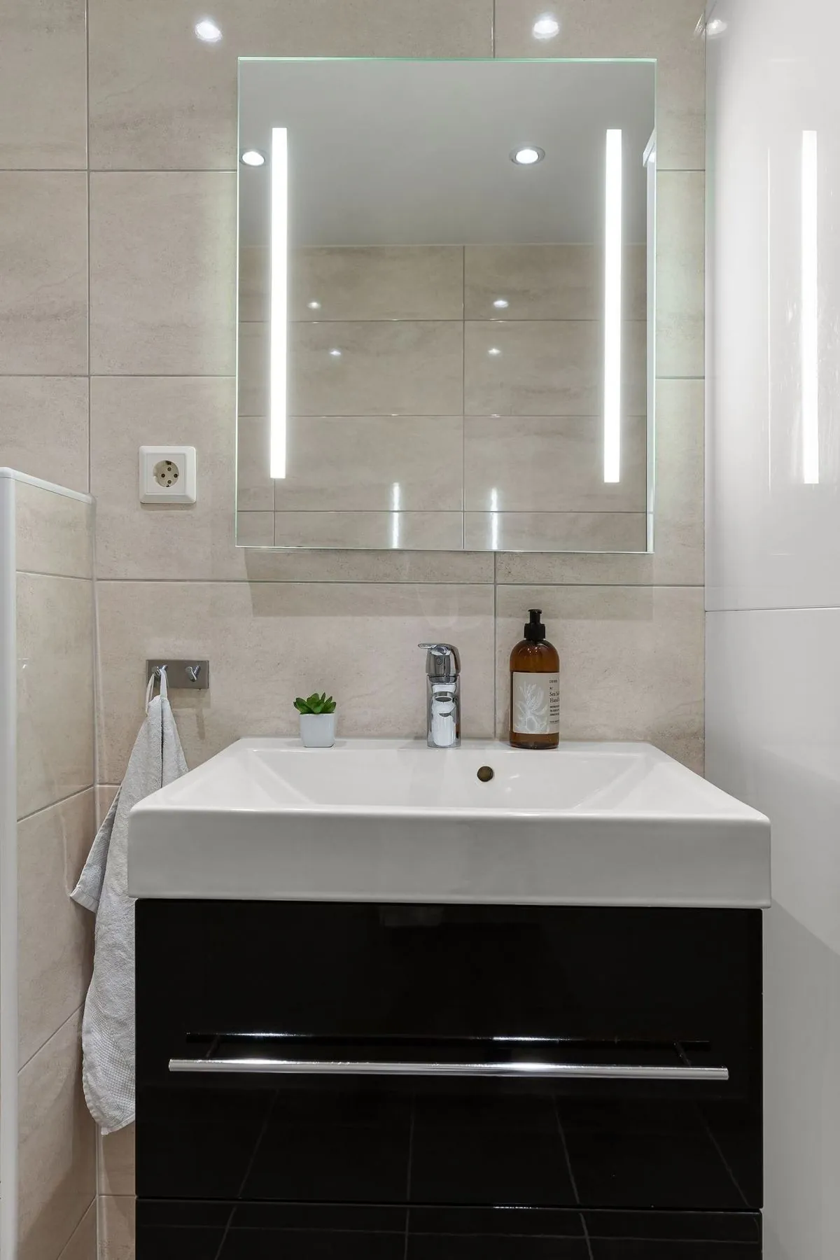 Lights reflecting in an illuminated bathroom mirror above the sink