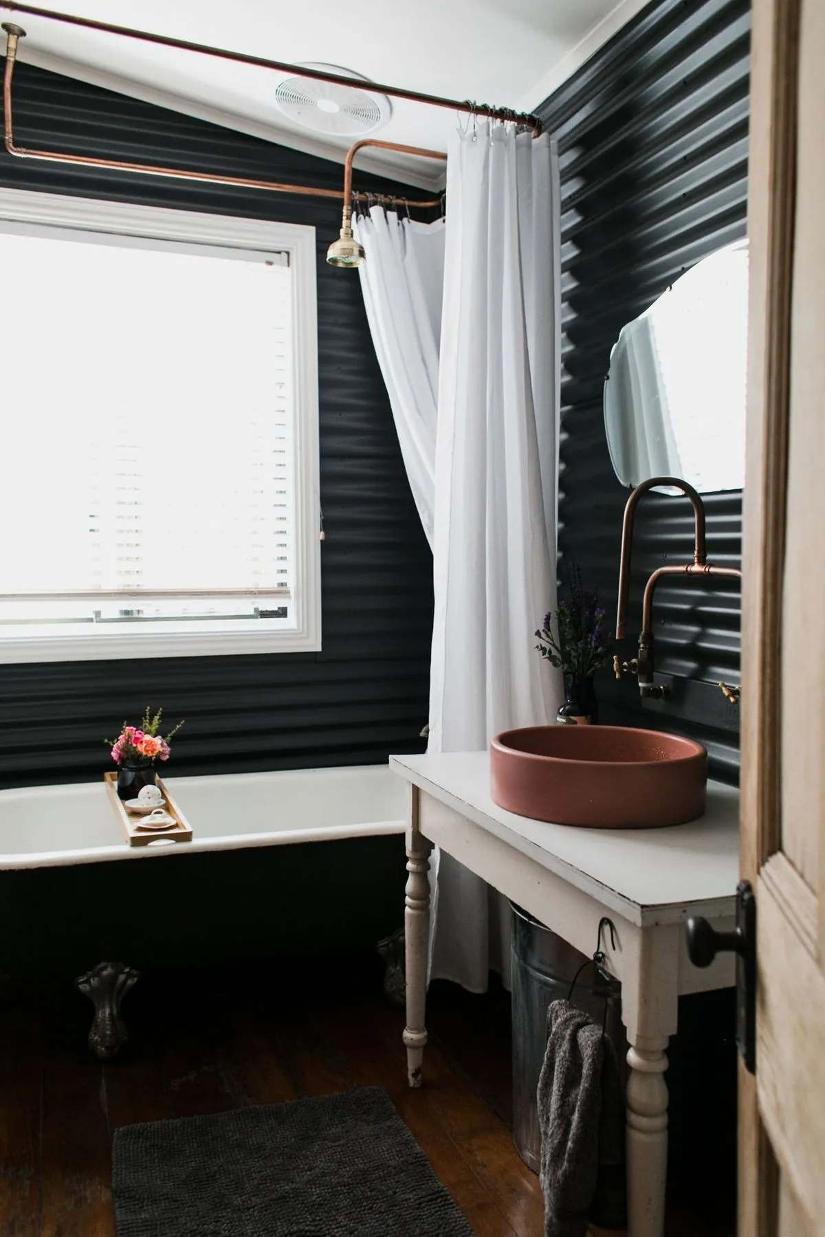 Vintage-style bathroom with a clawfoot tub, copper pipes and terracotta vessel sink.