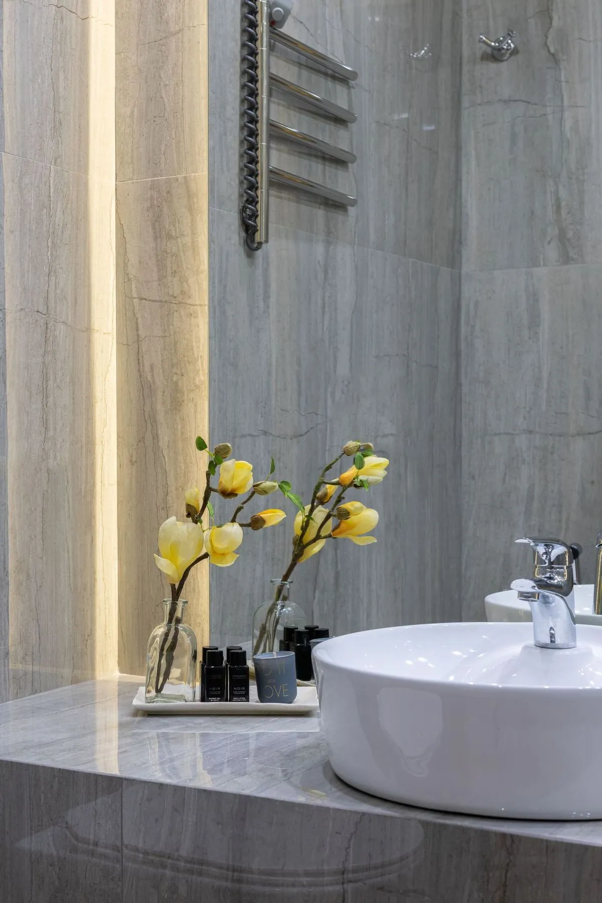 Stylish bathroom with modern sink and yellow flower decor on marble counter.