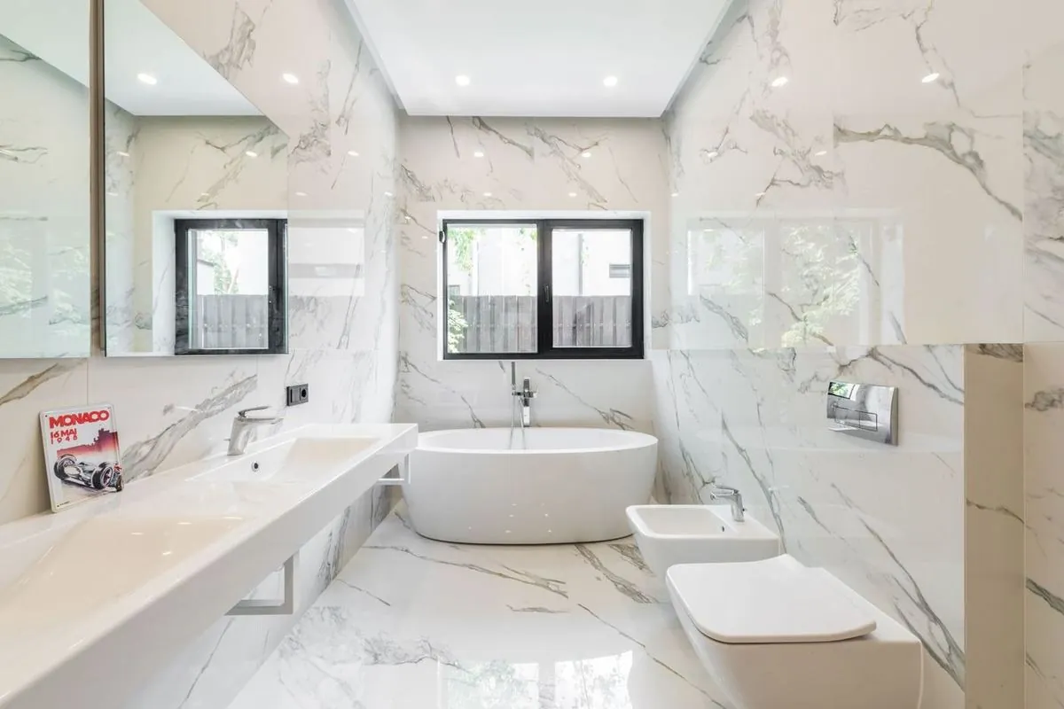 Marble bathroom interior with a bathtub, mirror and tiled walls.