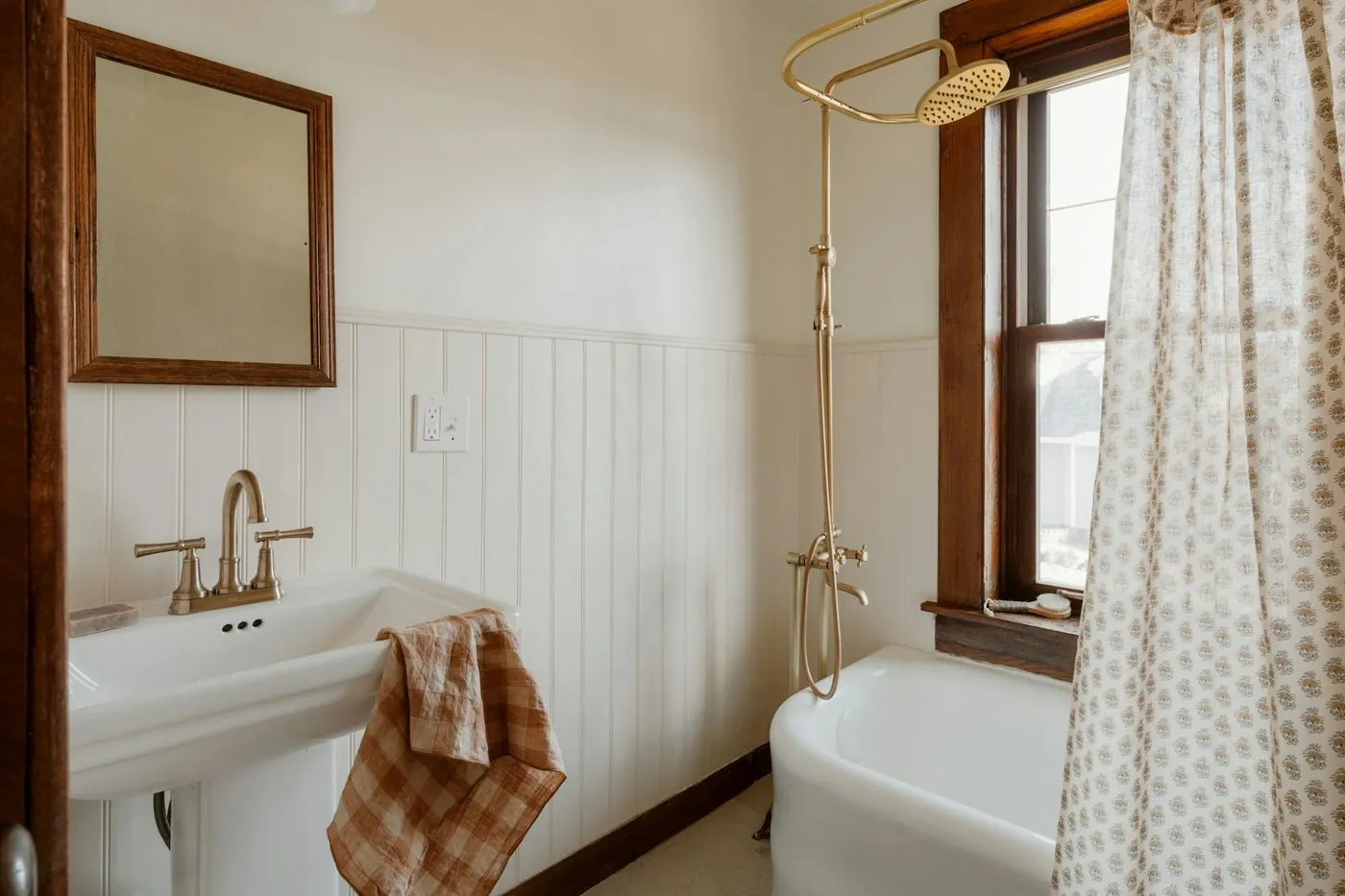 Remodeled farmhouse bathroom with clawfoot tub and wood vanity